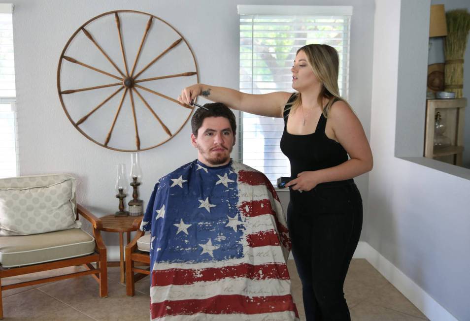 Brittany Seitz, a cosmetologist, combs her husband's, Michael, hair prior to demonstrating how ...