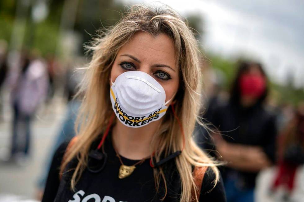 An artist, wearing a mask to protect against the spread of the coronavirus, protests outside th ...