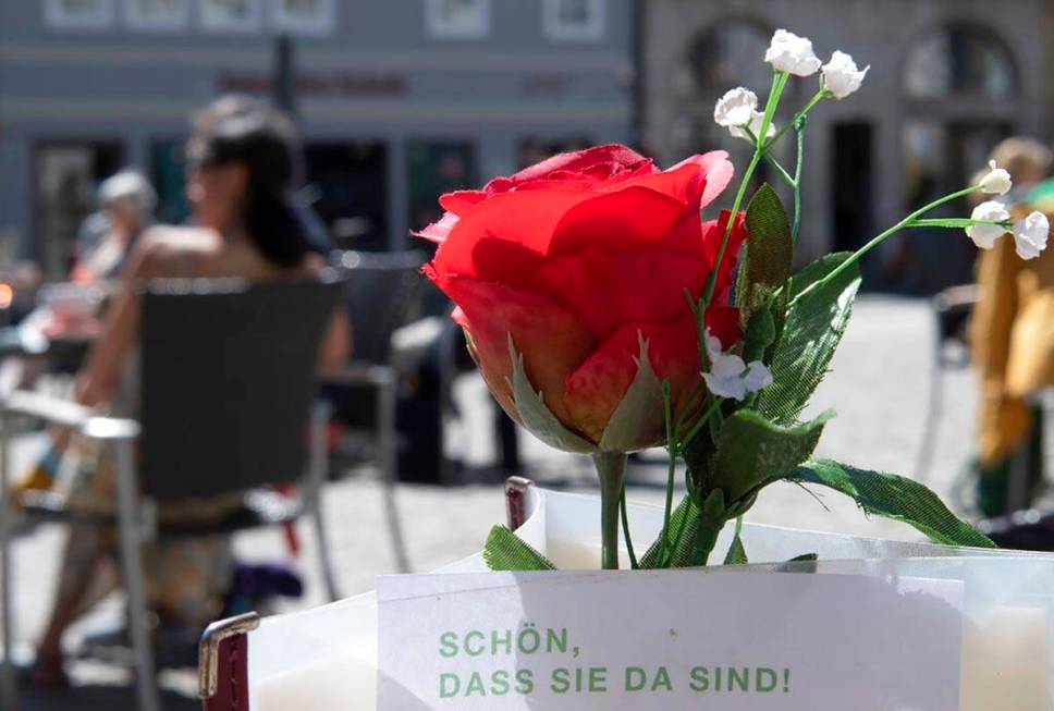 Restaurant guests relax behind a rose after the reopening of beer gardens in Weimar, central Ge ...