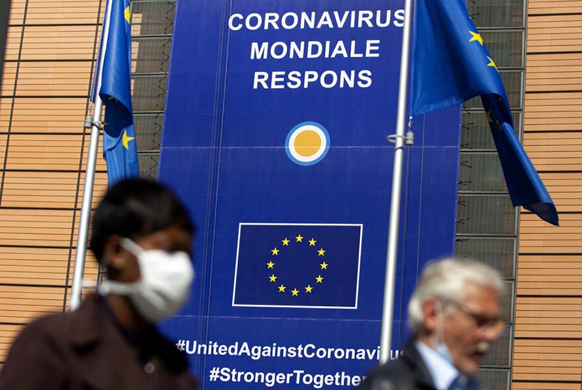 A woman wearing mouth mask, to prevent against the spread of the coronavirus, COVID-19, walks p ...