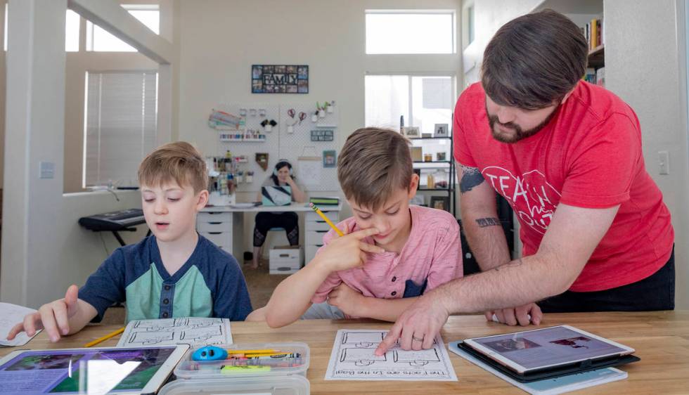 Twins Everett, left, and Atticus Mayville, 7, work on a school project with help from stepfathe ...