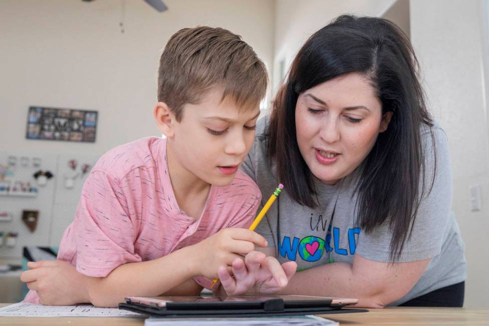 Atticus Mayville, 7, left, is helped by his mom Jessica Houchins, a middle school counselor, du ...