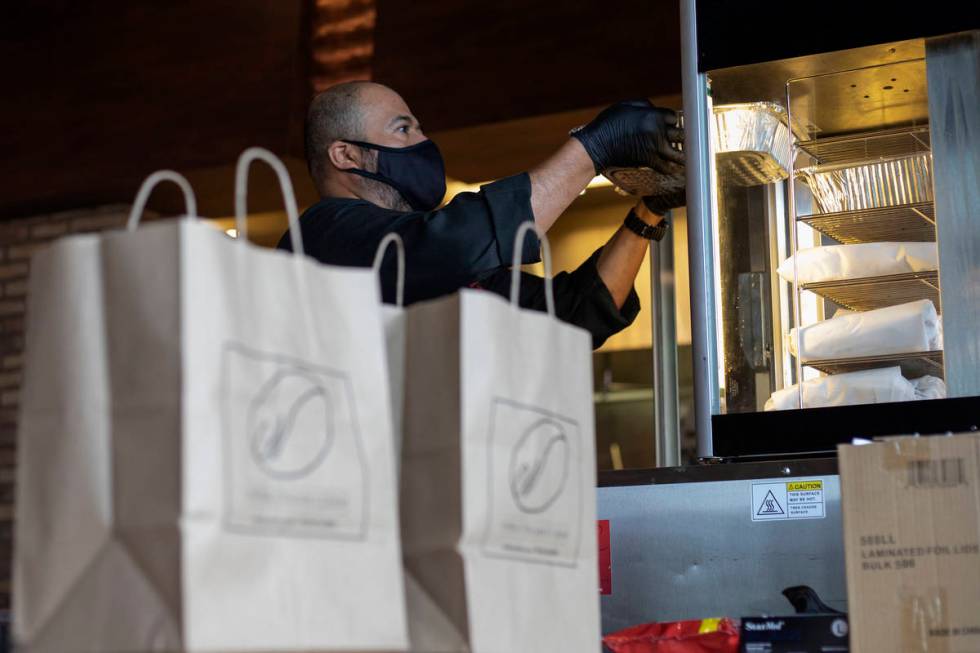 Misael Macias puts hot meals in a hot box as curbside pickup orders await customers at Nora's I ...