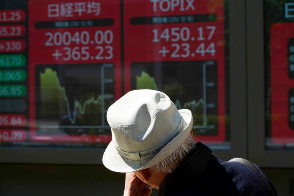 A man walks past an electronic stock board showing Japan's Nikkei 225 index at a securities fir ...