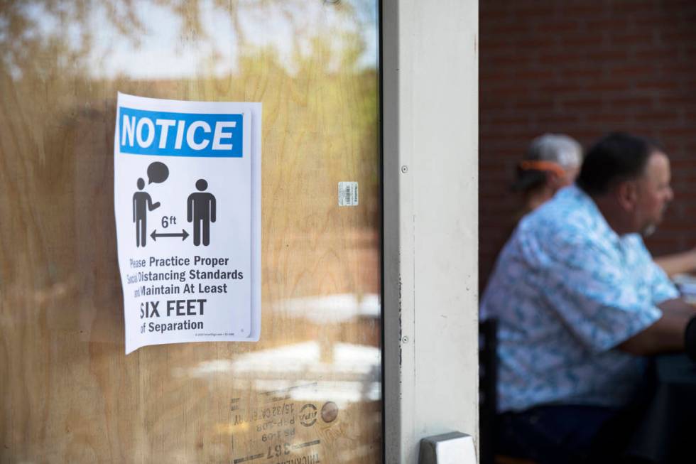 A sign to inform guests of social distancing measures on the door at 7th & Carson in Las Ve ...