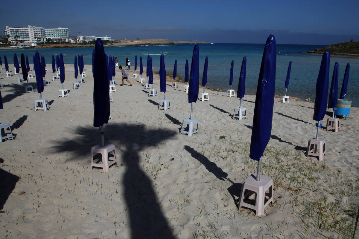 A boy walks among folded umbrellas on an empty stretch of "Nissi beach" in Ayia Napa, ...