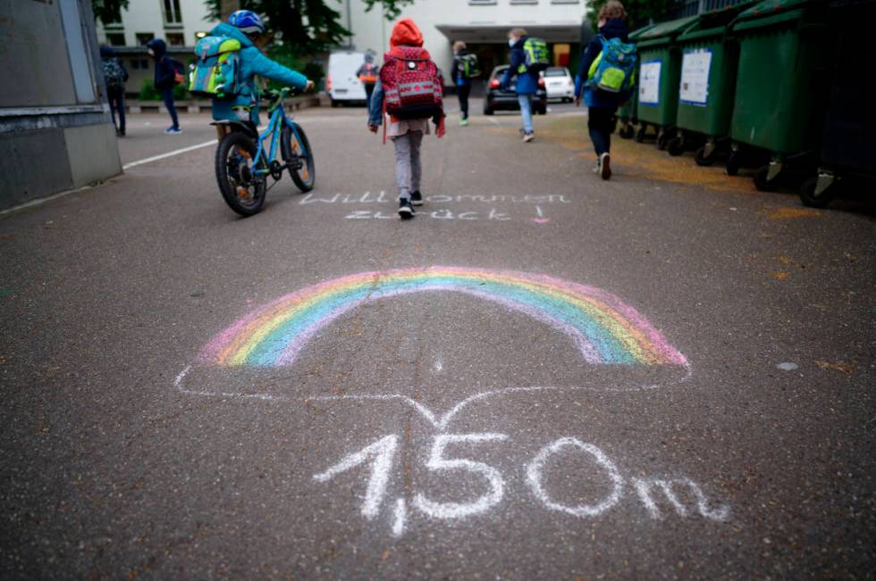 A writing on the ground remind students to keep distance as they arrive at a reopen primary sch ...