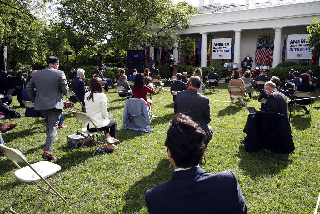 A reporter approaches a microphone to ask as question of President Donald Trump during a briefi ...