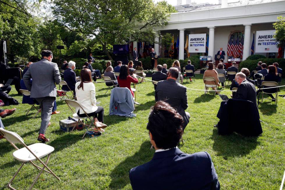 A reporter approaches a microphone to ask as question of President Donald Trump during a briefi ...