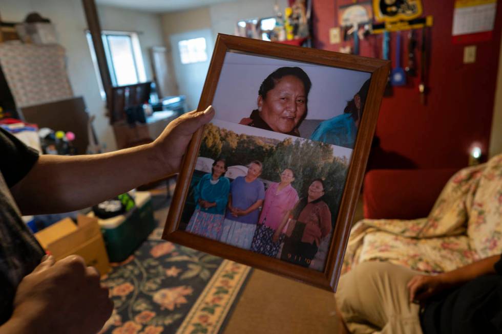 Eugene Dinehdeal holds photos of family members, including Eva Dinehdeal at top, at the Dinehde ...