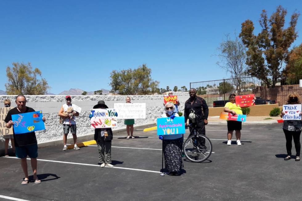 Seniors at Nevada HAND's Flamingo Pines senior community display "thank you" signs for the nonp ...