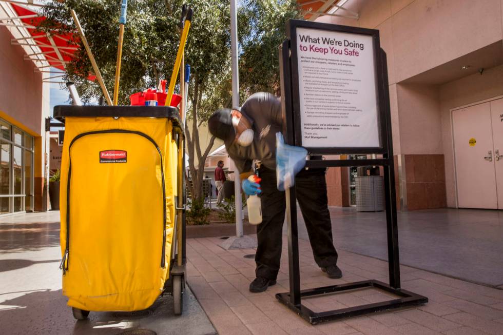 Ivan Leybe sanitizes one of the many customer information signs now installed throughout the La ...