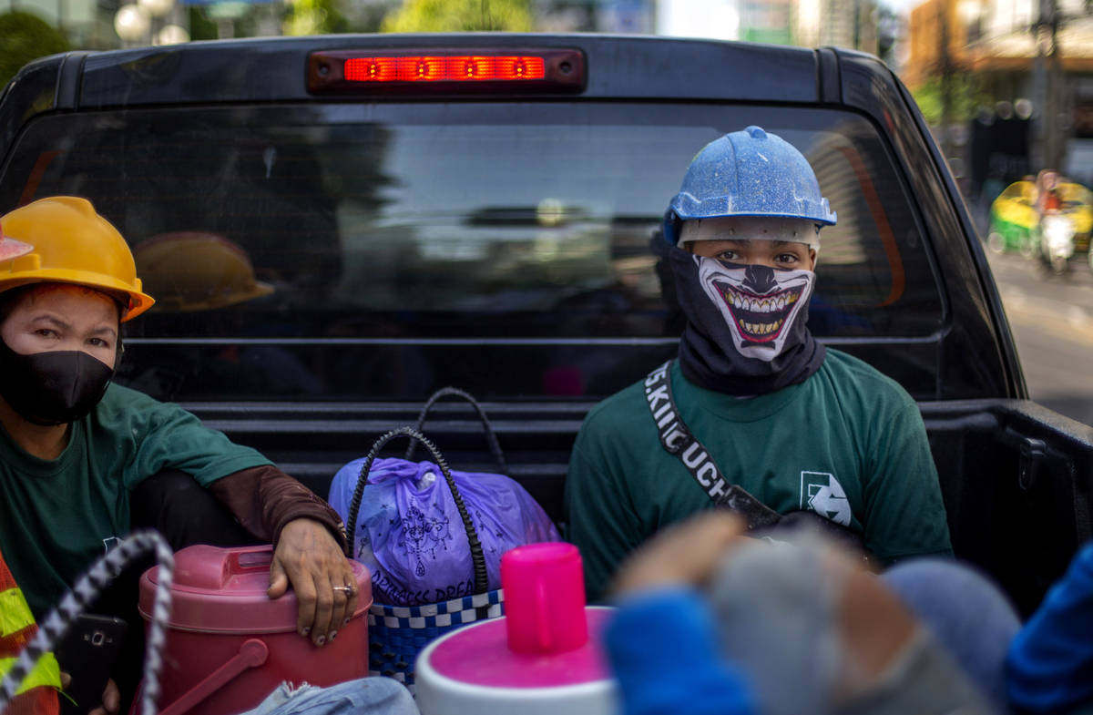 Construction workers wearing face masks travel in a back of a crew cab in Bangkok, Thailand, We ...