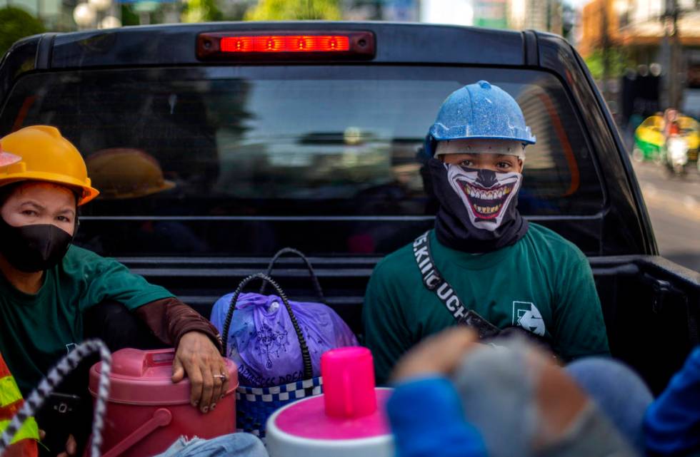 Construction workers wearing face masks travel in a back of a crew cab in Bangkok, Thailand, We ...