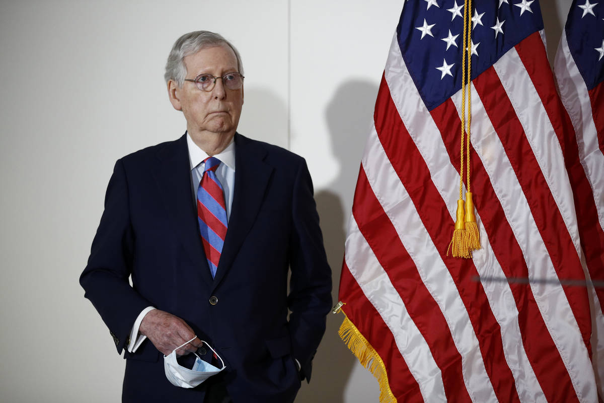 Senate Majority Leader Mitch McConnell of Ky., holds a face mask used to protect against the sp ...