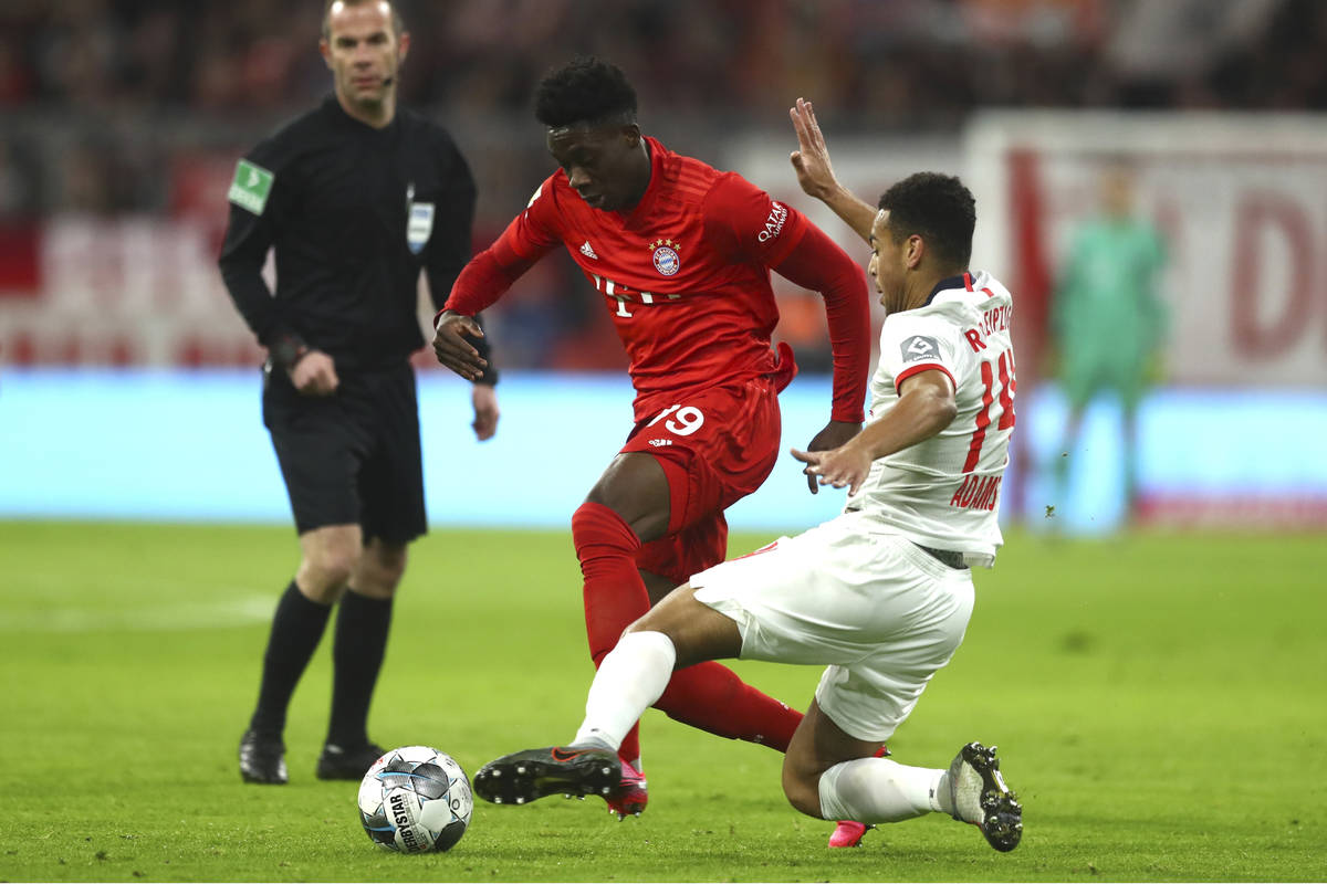 Bayern's Alphonso Davies, centre, and Leipzig's Tyler Adams challenge for the ball during the G ...