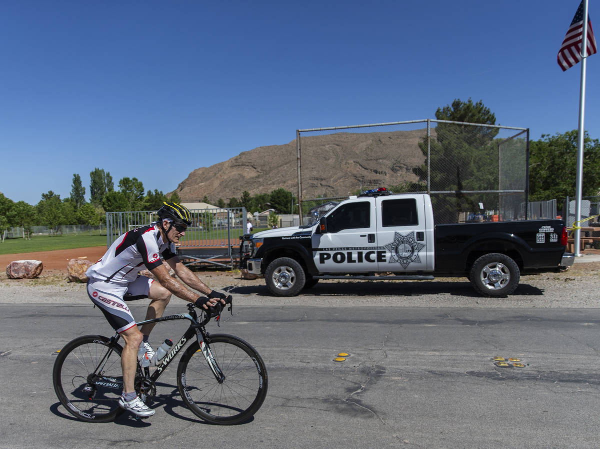 A cyclist passes a Las Vegas police vehicle stationed at Blue Diamond Park on May 13, 2020, aft ...