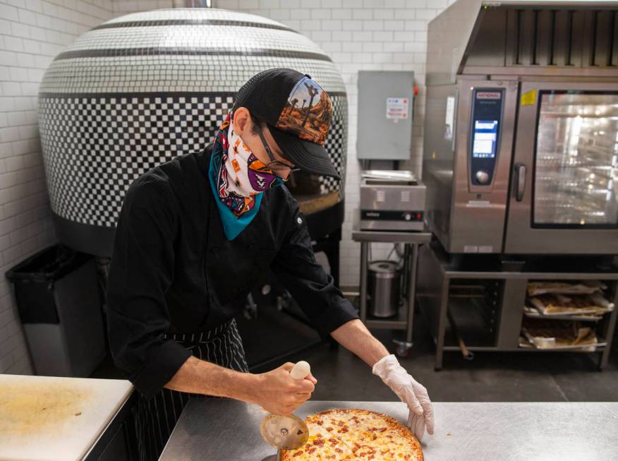 Roberto Raimúndez, a cook at Cottonwood Station, slices a pizza on Wednesday, May 13, 2020, in ...