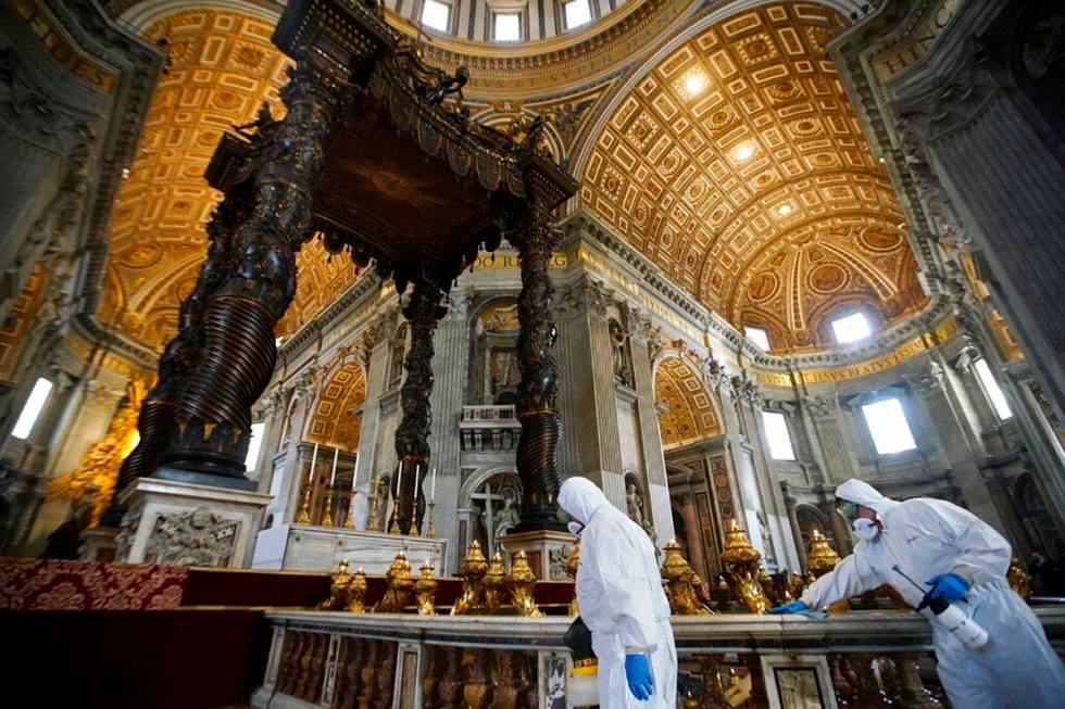 Workers in protective gear sanitize beneath the baroque sculpted bronze canopy of St. Peter's B ...