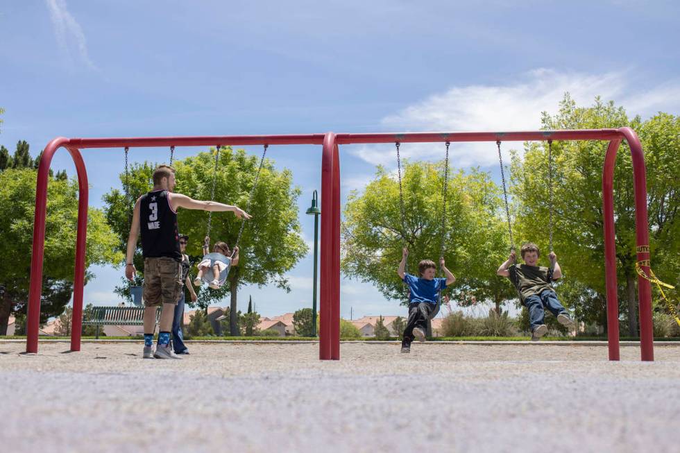 David Cotterell and Mikayla Fitzgerald push 2-year-old Rhiannon Fitzgerald's swing, left, as 8- ...