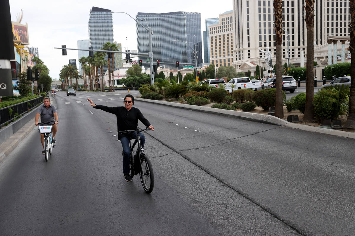 Mr. Las Vegas Wayne Newton, right, waves to fans while riding a bicycle on the Strip in Las Veg ...