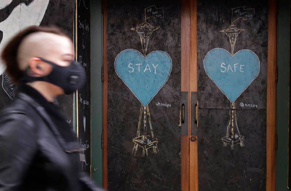 A pedestrian wearing a face mask walks past art by the street artist @dozfy, featuring the Spac ...