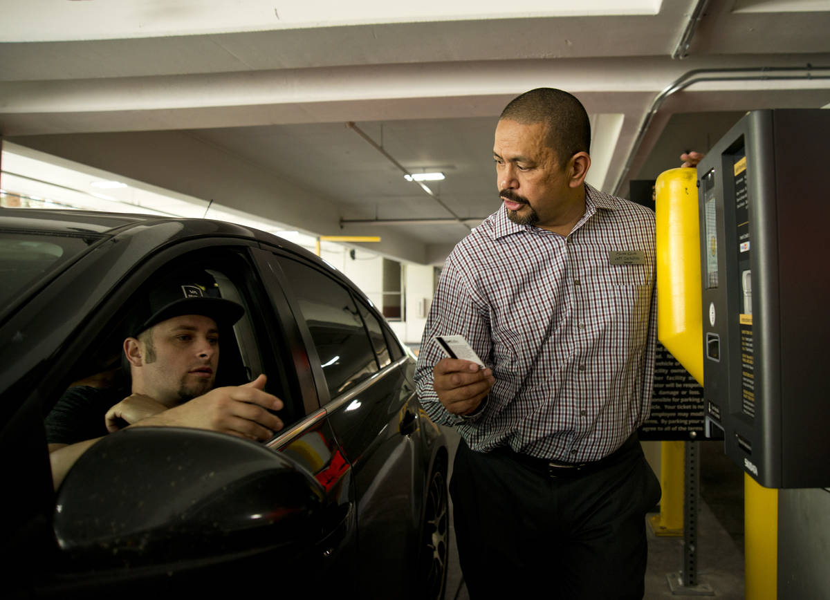 Jeff Carbullido helps a visitor exit the parking garage on the first day of paid parking at the ...