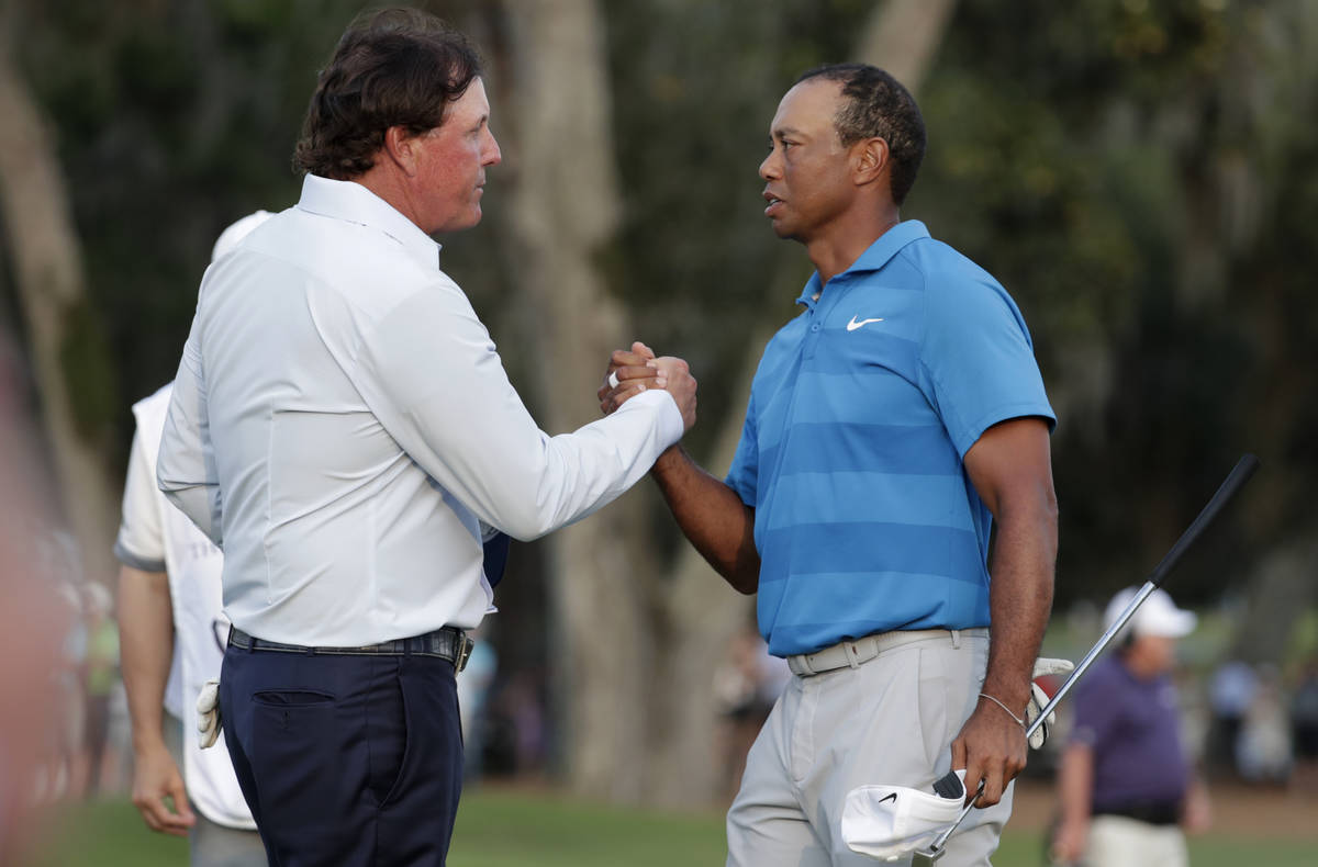 In this May 10, 2018, file photo, Phil Mickelson, left, and Tiger Woods shake hands after the f ...