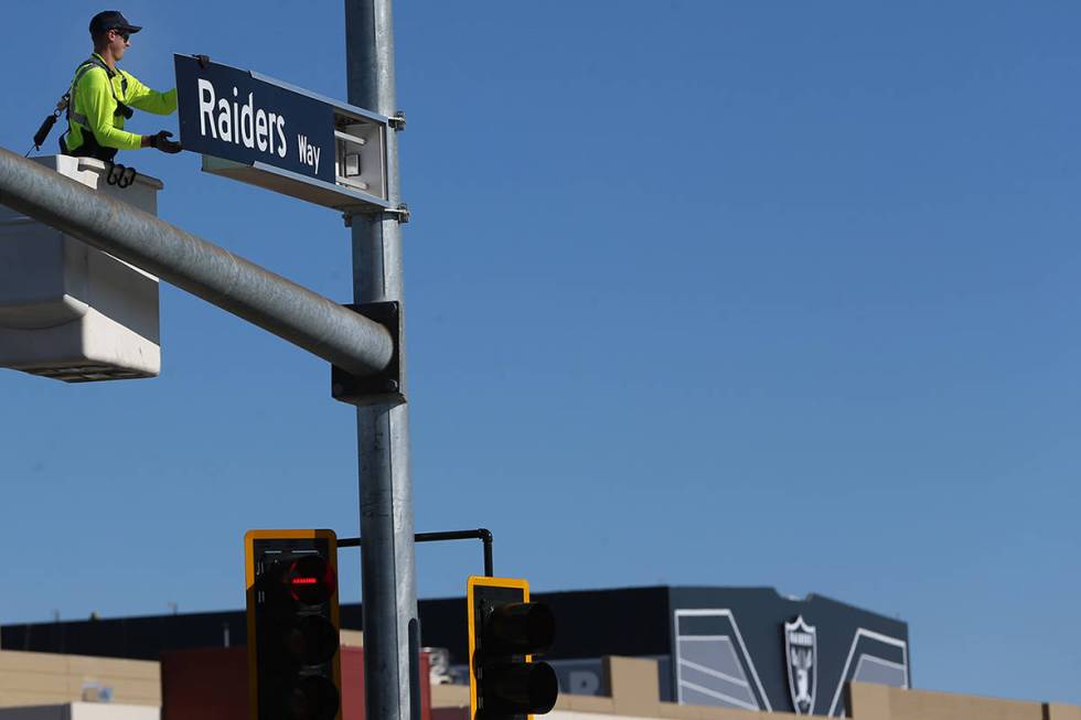 Justin Buhl, a traffic signal technician for the city of Henderson, installs a Raiders Way stre ...