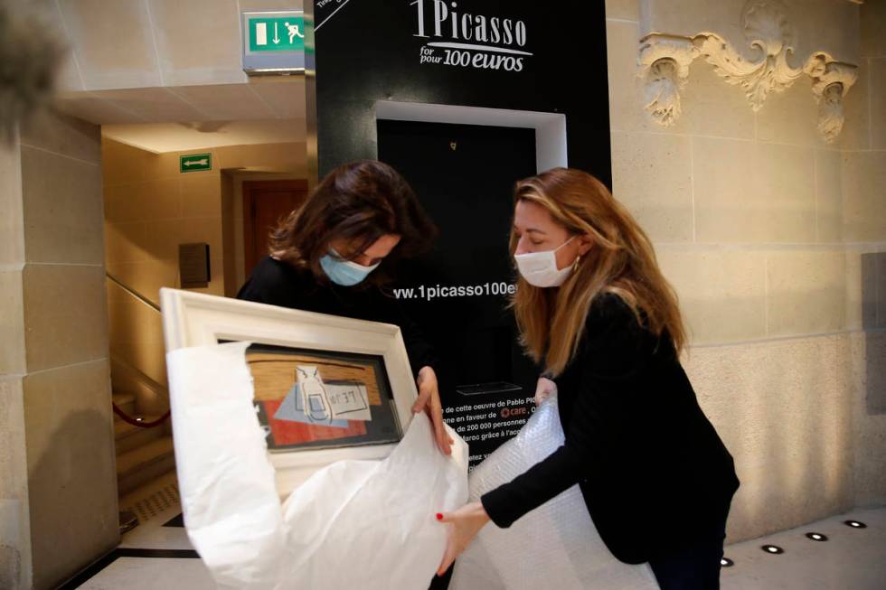 Raffle organizers Peri Cochin, left, and Arabenne Reille unbox the painting "Nature morte& ...