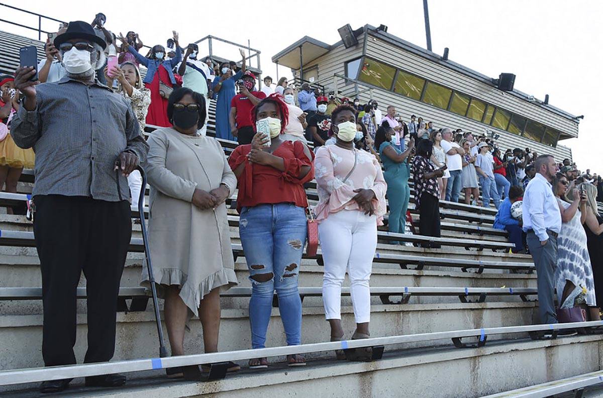 In this Monday, May 12, 2020 photo, families wore masks and practice social distancing during C ...