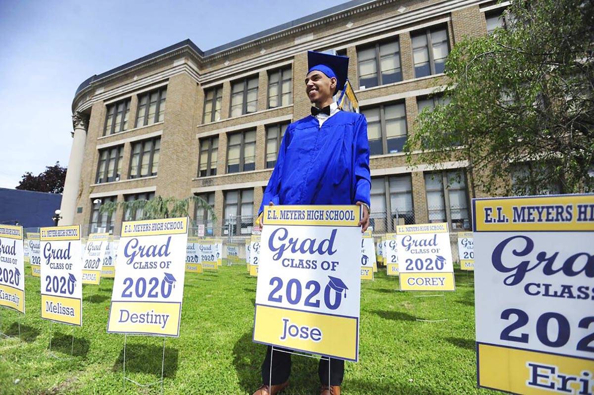 E. L. Meyers High School graduate Jose Sepulveda poses for family pictures while holding his gr ...