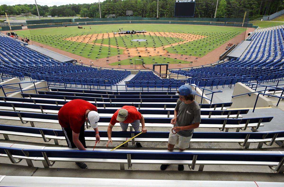 Workers use tape to block off seats as they prepare for a large high school graduation ceremony ...