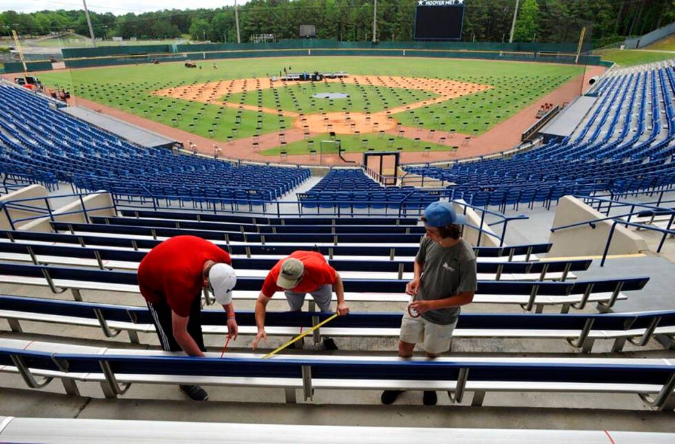 Workers use tape to block off seats as they prepare for a large high school graduation ceremony ...