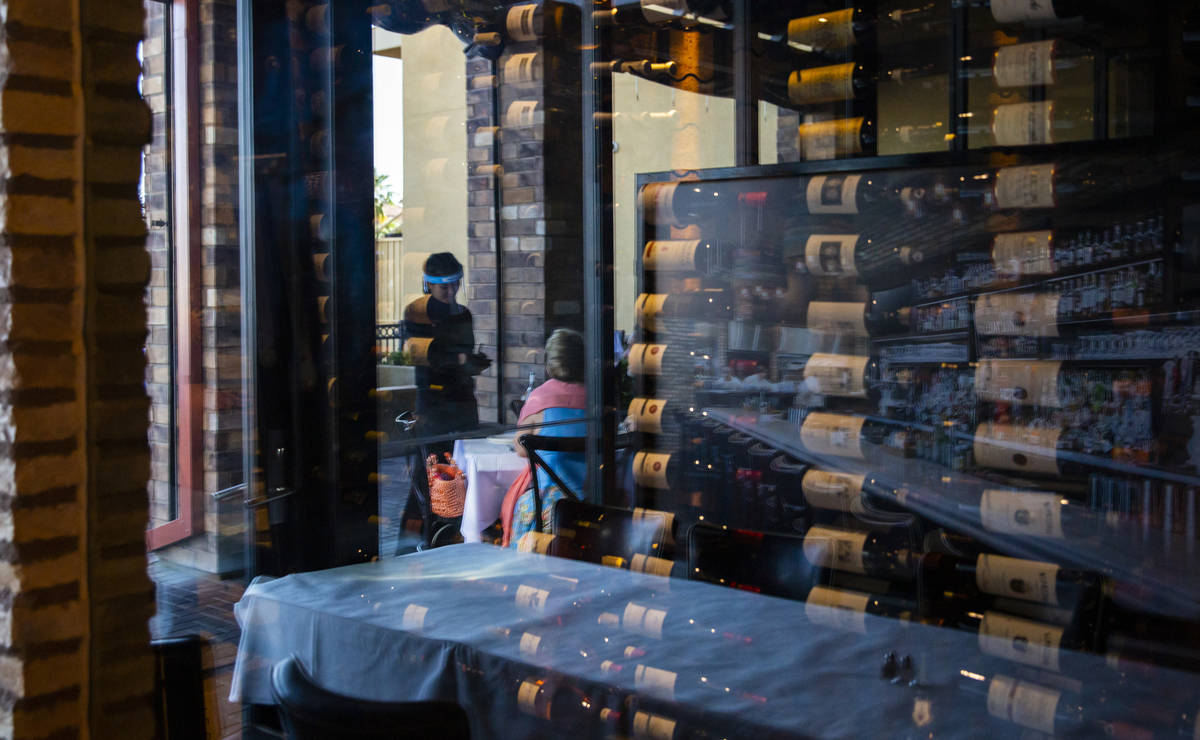 A server wears a face shield while helping diners at Nora's Italian Cuisine in Las Vegas on Thu ...