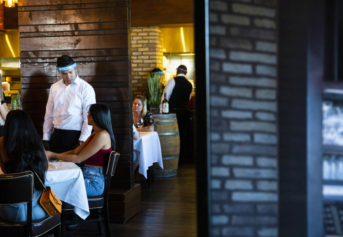 Ramon Mora wears a face shield while serving diners at Nora's Italian Cuisine in Las Vegas on T ...