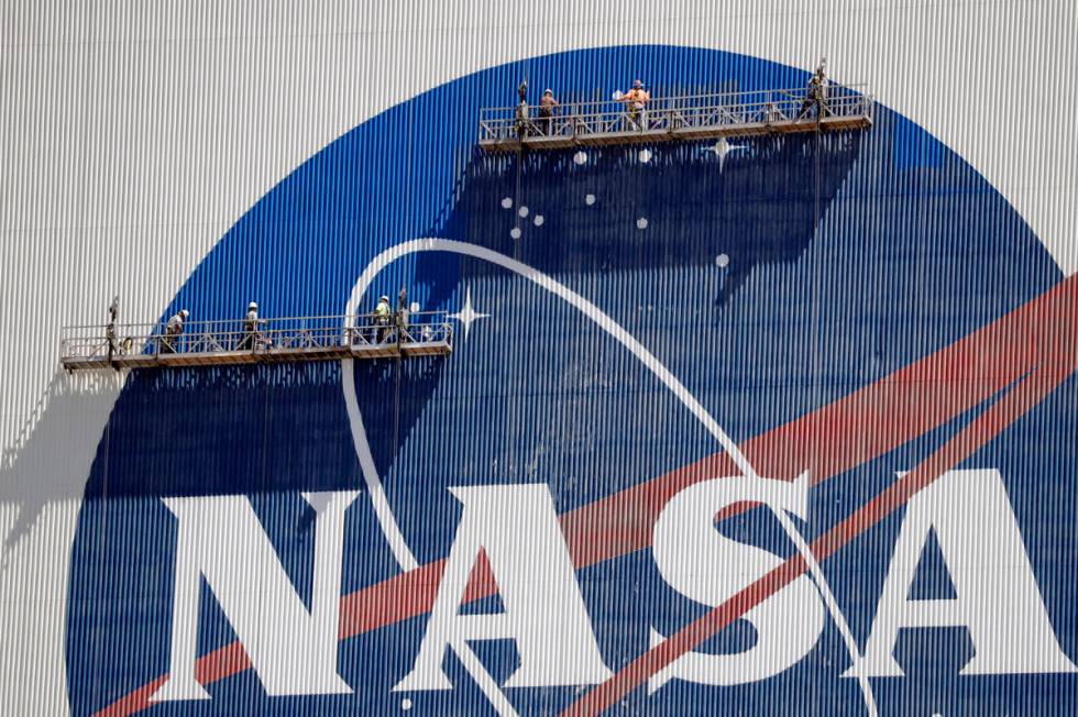 Workers near the top of the 526 ft. Vehicle Assembly Building at the Kennedy Space Center spruc ...