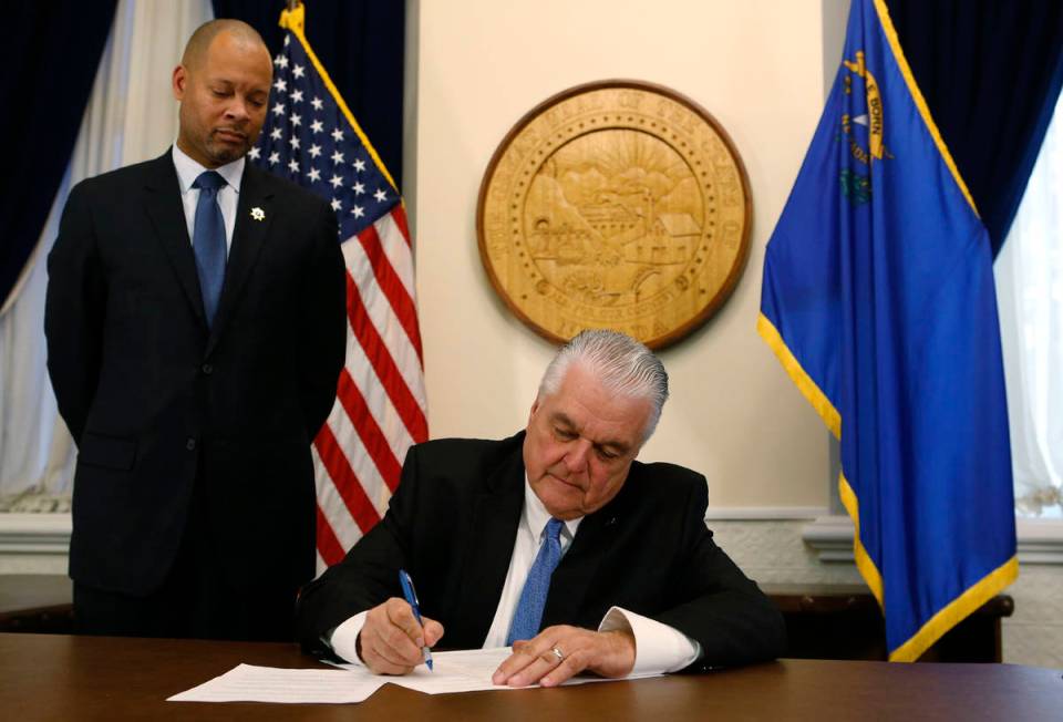 Nevada Gov. Steve Sisolak signs his first executive order. (Cathleen Allison/Las Vegas Review-J ...