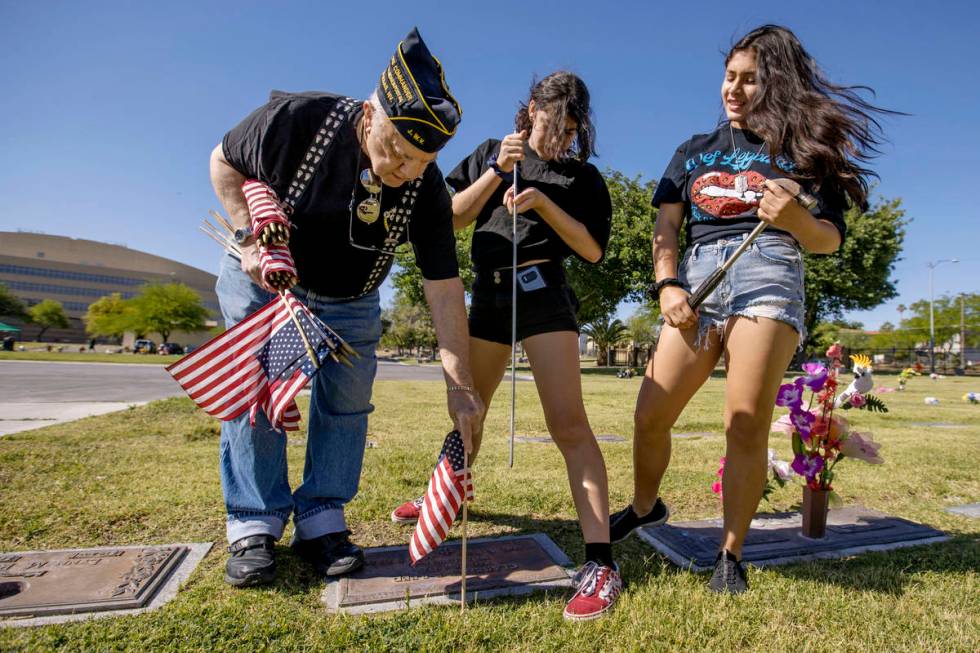 Army veteran Howard Greenspon, left, plants another American flag on a veteran's grave with the ...