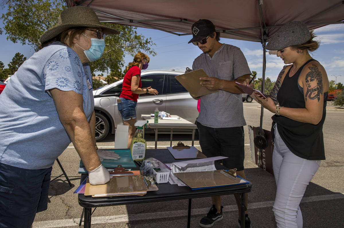 Henderson Coalition for Responsible Government volunteer Laura Sanchez, left, helps to get sign ...