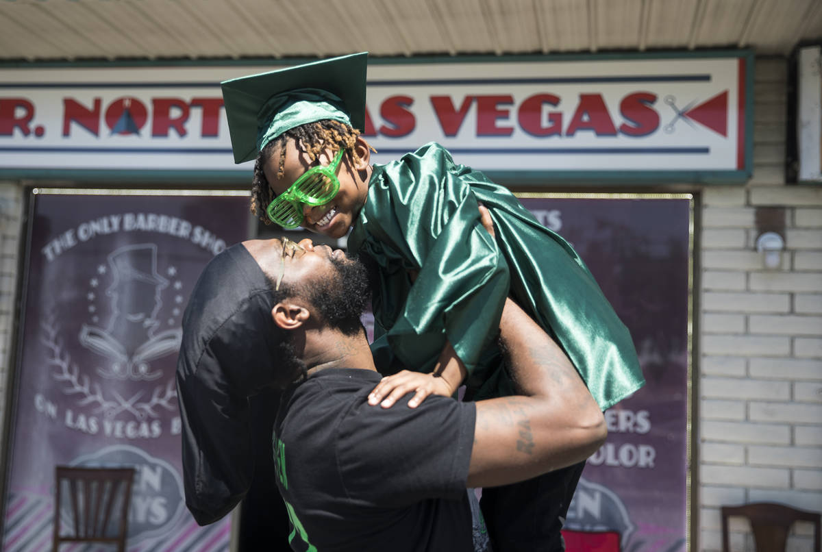 Morgan Harris holds up his son Messiah Harris, 6, after having his kindergarten graduation phot ...