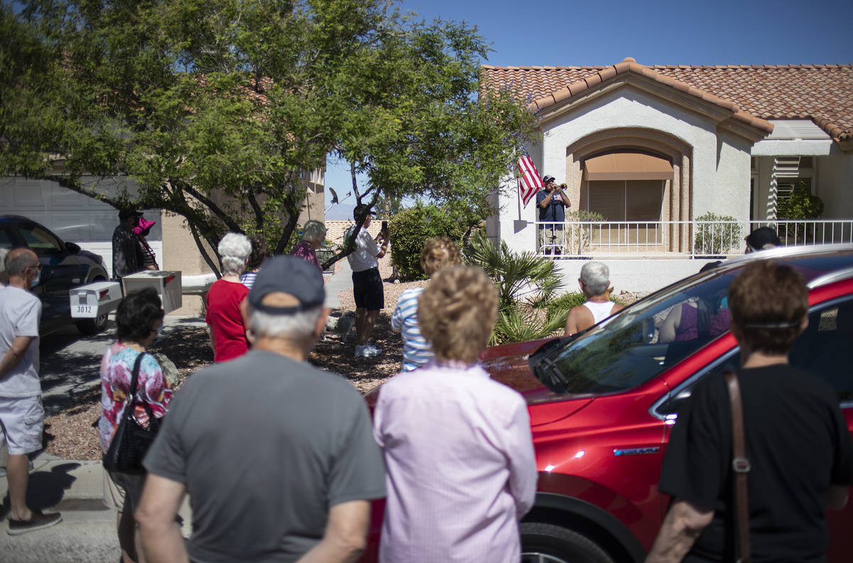 Friends and neighbors watch as Bob Altomondo, who played trumpet in the Navy, plays TAPS outsid ...