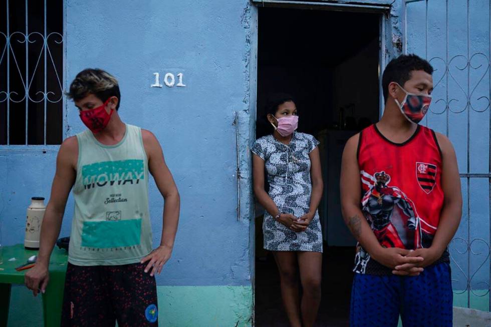 Caregiver Leandro Beiton, left, and relatives of the late Edgar Silva, wearing face masks amid ...