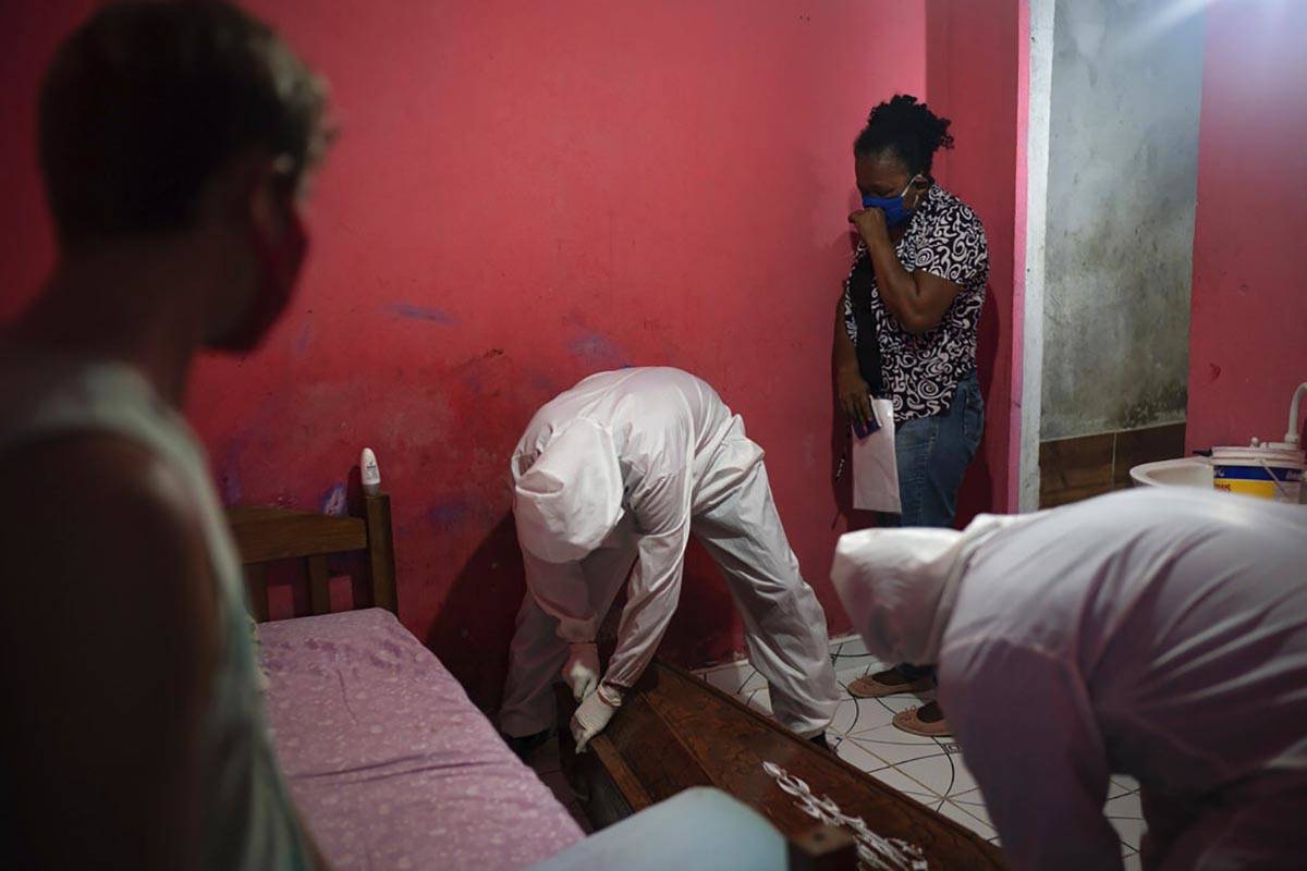 Eliete das Graças, top right, cries as SOS Funeral workers, wearing protection equipment, ...