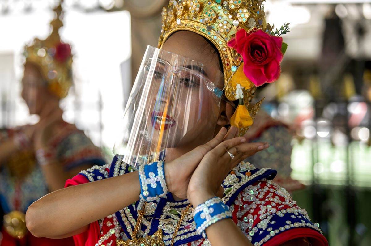 A Thai classical dancer wearing face shield to help curb the spread of the coronavirus performs ...