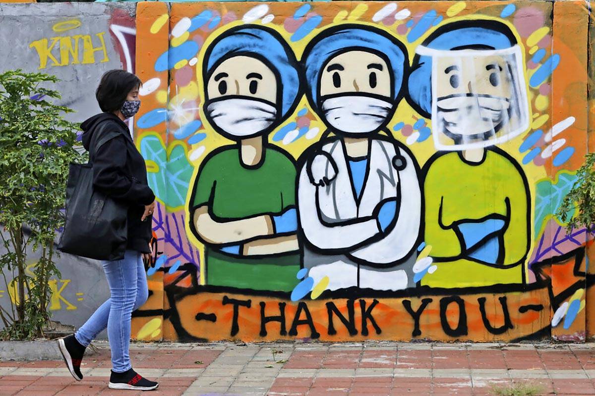 A woman walks past a mural honoring health care workers during the new coronavirus outbreak in ...