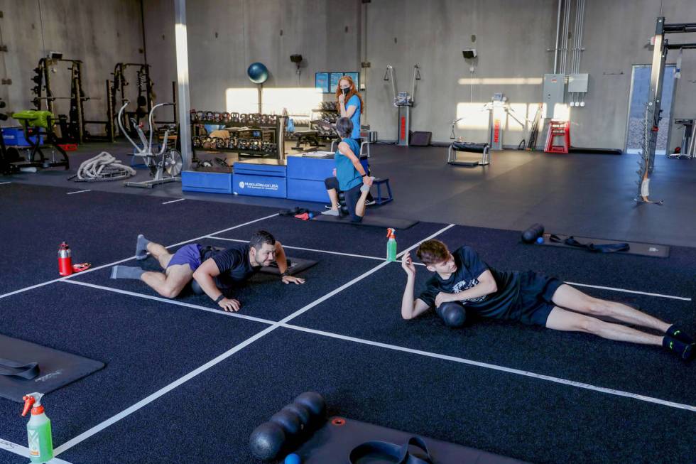 Members of The Gym Las Vegas Brian Lee, left, and Ethan Ryan, 17, stretch while following socia ...