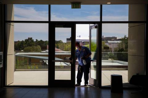 Robert Lucas, left, a custodian supervisor, sanitizes a door in the Hospitality Hall at UNLV in ...