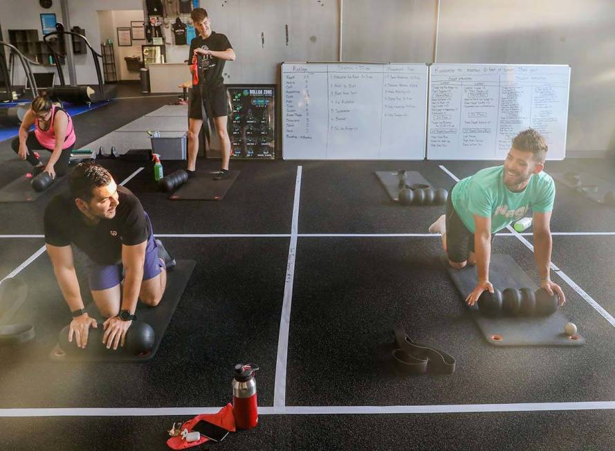 Members of The Gym Las Vegas Brian Lee, left, and Ethan Ryan, 17, stretch while following socia ...