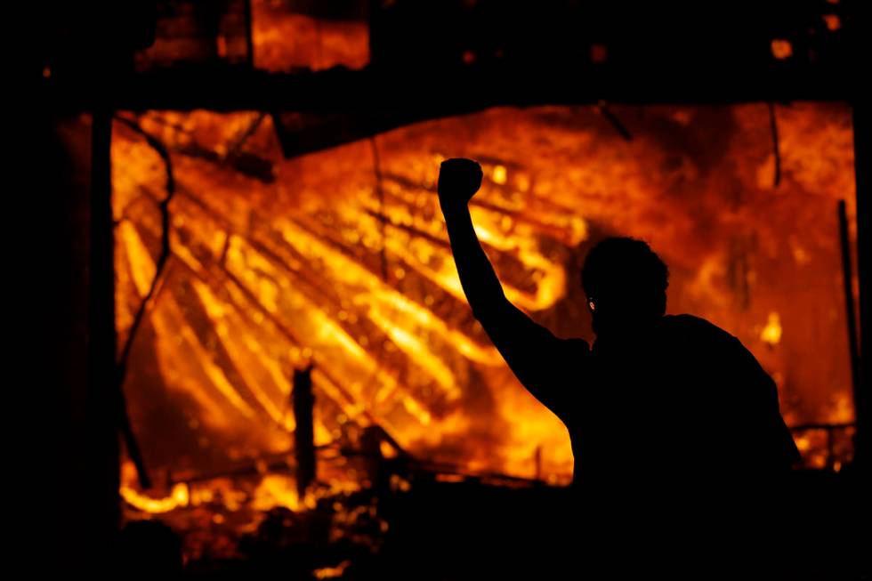 A protester gestures in front of the burning 3rd Precinct building of the Minneapolis Police De ...